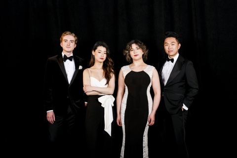 Four people dressed in black tie (two men, two women) pose in front of a black background