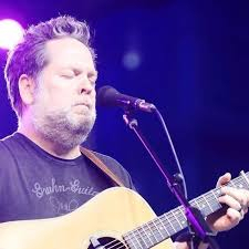 A guitarist performs on stage with his eyes closed