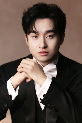 Headshot of a man wearing a black suit jacket and white dress shirt