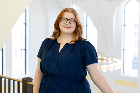 Headshot of a woman with a navy blue shirt and red hair