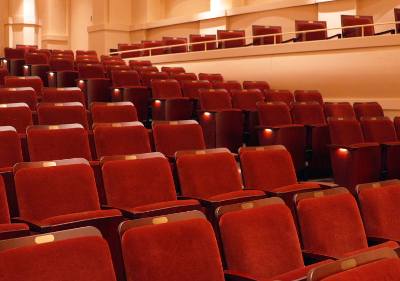 Newly renovated audience chairs in Duncan Recital Hall with red seat cushions and dark wood