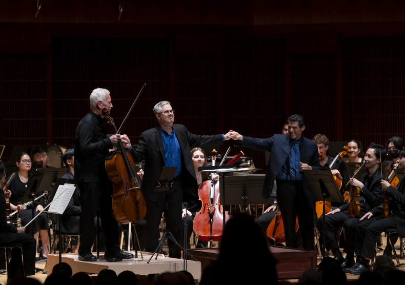Three men – Fischer, Brandt, and Harth-Bedoya – standing in front of an orchestra acknowledge audience's applause