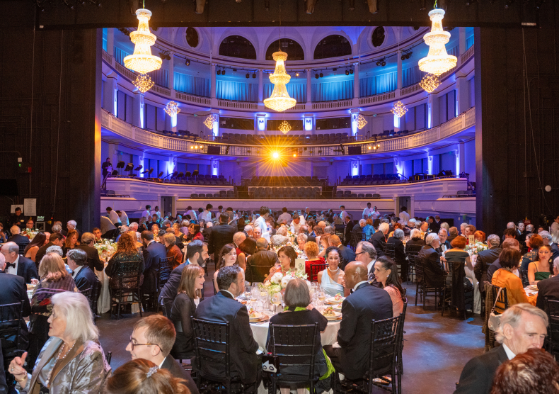 View from inside Morrison Theater as guests in black-tie attire enjoy dinner on stage