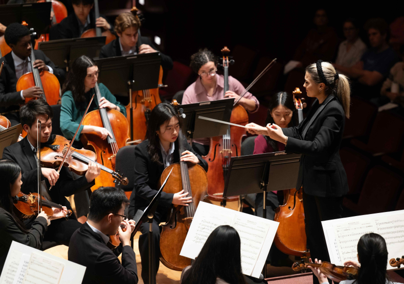 Orchestra performance photo featuring cellists and violists in colorful shirts