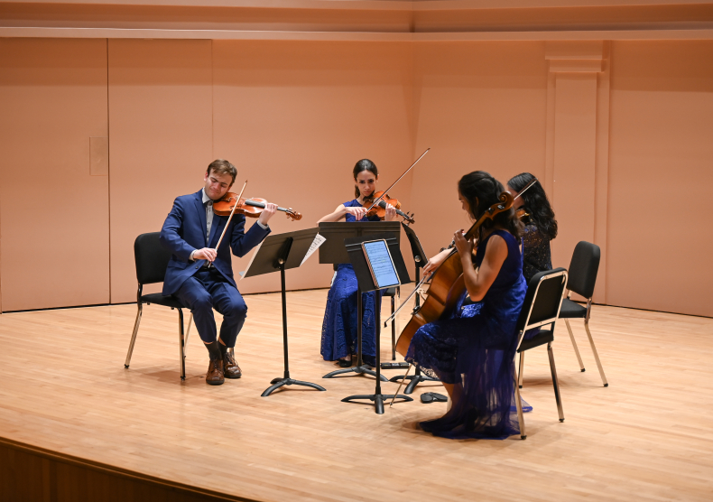 A string quartet in blue outfits performs on the Duncan Recital Hall stage
