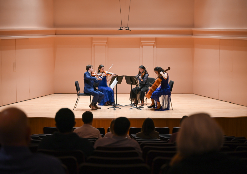 A string quartet in blue outfits performs on the Duncan Recital Hall stage