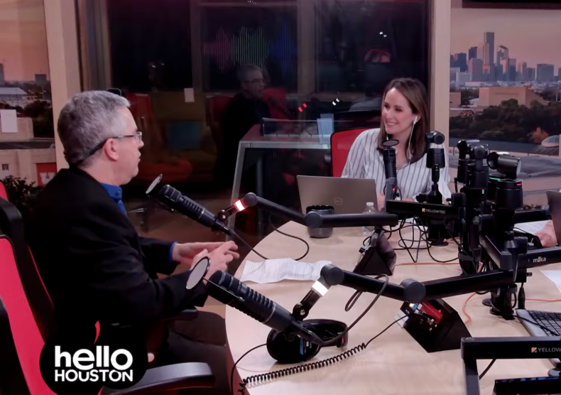 Two people in a radio studio look at each other while conversing