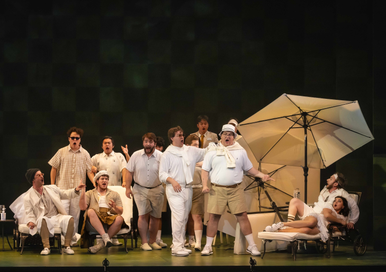 An ensemble of vocalists wearing beige and white country club outfits perform in front of a green set