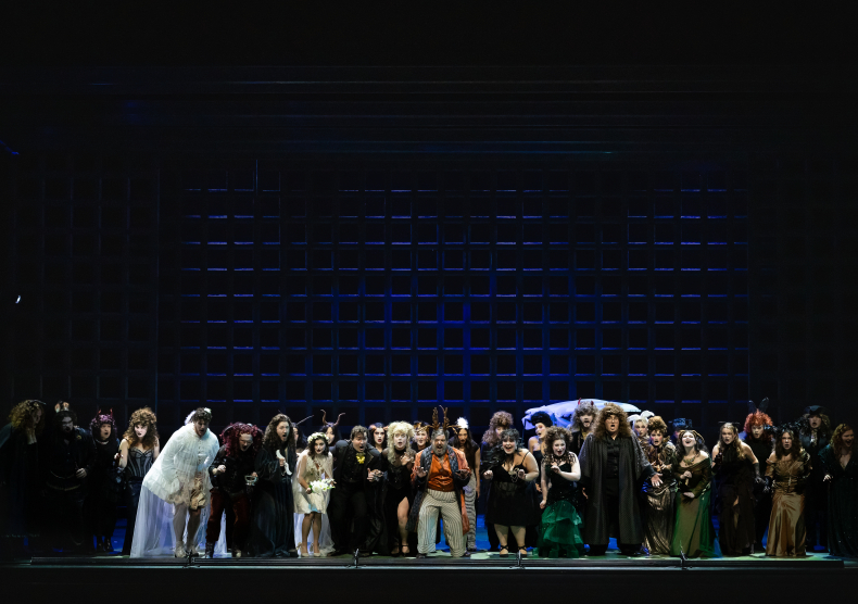 Photo of opera students on stage in mystical costumes performing in front of a dark blue set