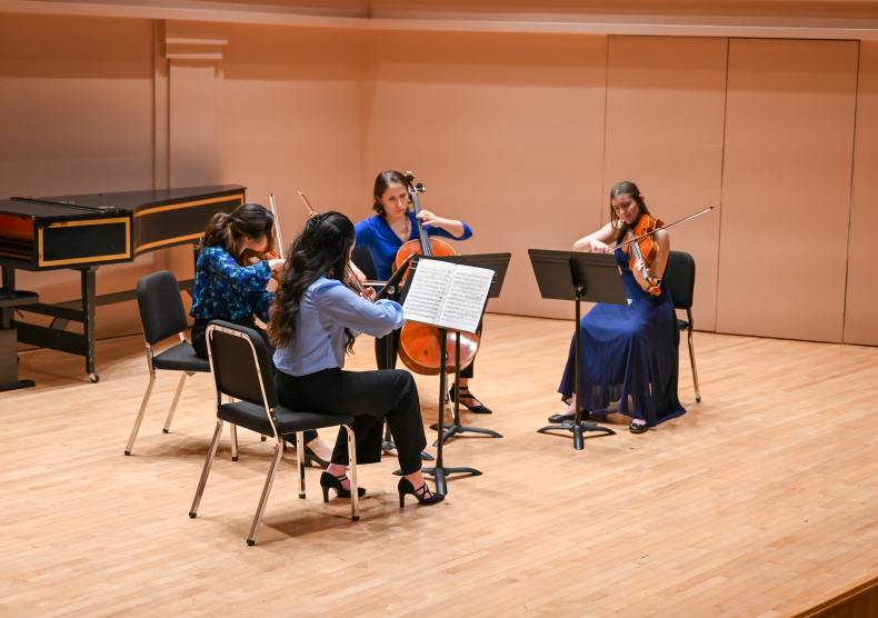 A string quartet in blue outfits performs on the Duncan Recital Hall stage