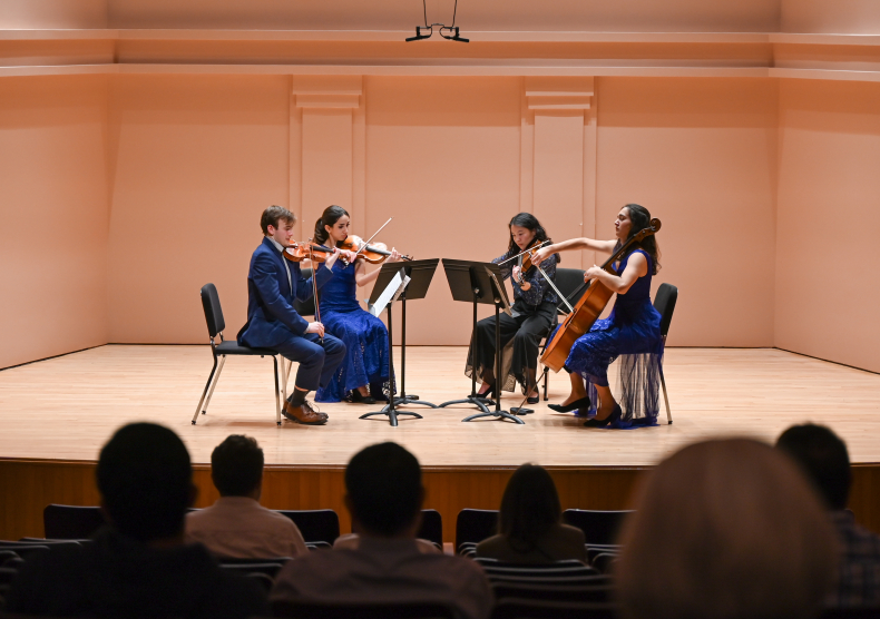 A string quartet in blue outfits performs on the Duncan Recital Hall stage