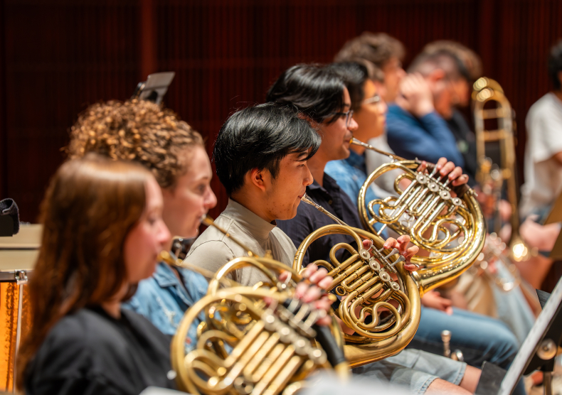 Four french horn players in rehearsal and casual clothing