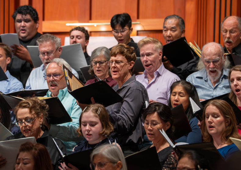 A group of musicians holding binders sing and perform