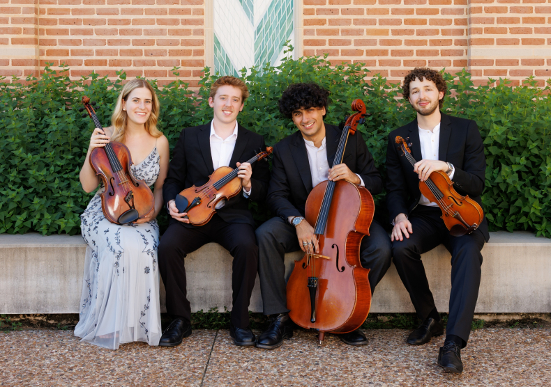 Four musicians sit with their string instruments on an outdoors bench